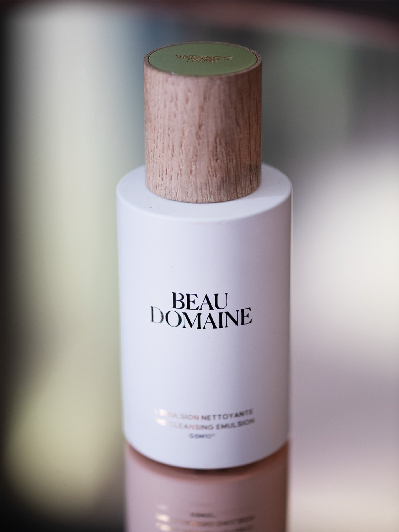 Beau Domaine skincare bottle with wooden cap on a blurred background